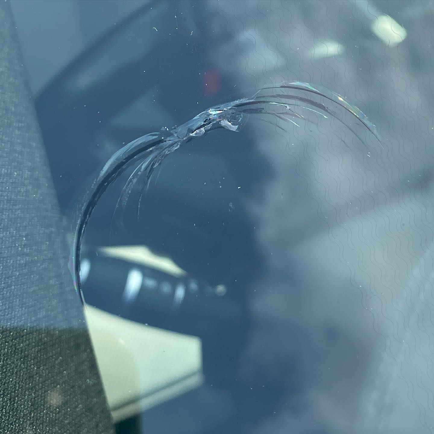 A close-up of a cracked windshield in a car, highlighting the damage
