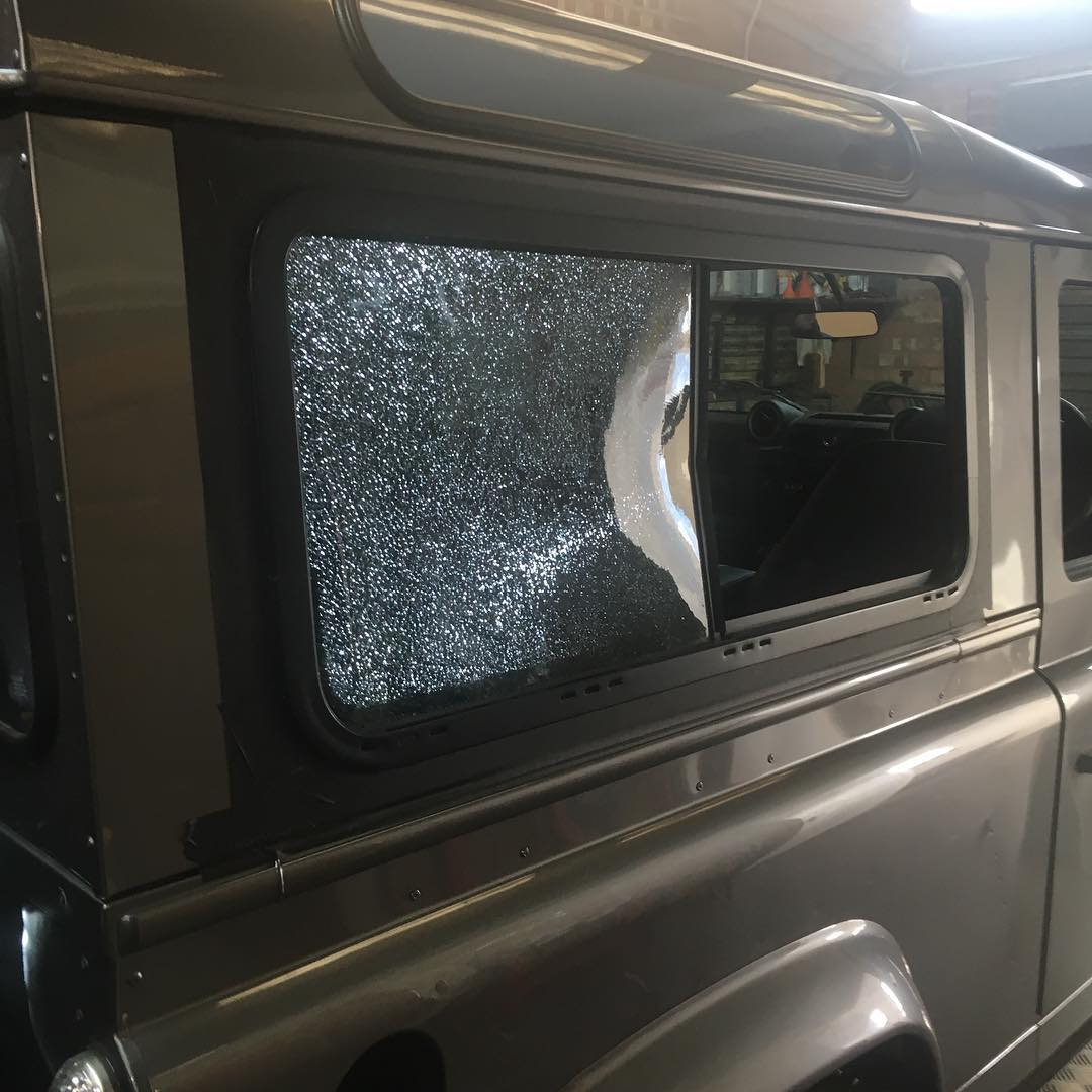 A vehicle with a broken window, showing signs of damage and in need of a window replacement.